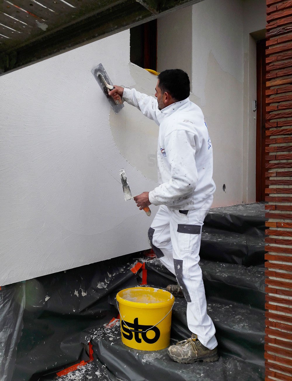 Artisan FCA appliquant un enduit de façade sur échafaudage à Saint-Étienne